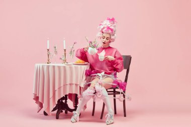 Pembe stil festival masası. Zarif prenses portresi, pembe elbiseli kraliçe ve pembe arka planda çay içen peruk. Devir, modernlik ve rönesans, güzellik ve tarih karşılaştırması kavramı