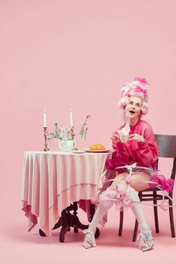 Sabah kahvaltısı. Komik prensesle portre, zarif kıyafetler giyen kraliçe ve pembe arka planda çay içen peruk. Devir, modernlik ve rönesans, güzellik ve tarih karşılaştırması kavramı