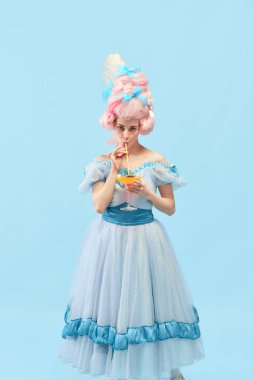 Tatilde. Genç prenses portresi, zarif kıyafetler giyen kraliçe ve mavi stüdyo arka planında peruk içen kokteyl. Devir, modernlik ve rönesans kavramı, rahatlatıcı, parti