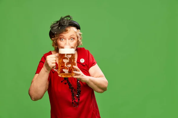 新鮮なビールのドラフト 女性との肖像画 大きなビールマグカップを保持し 緑の背景に飲むヴィンテージの赤いドレスを身に着けている女性 オクトーバーフェスト 広告のコンセプト — ストック写真