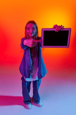 Online okul. Güzel bir kız, şık giyinmiş bir öğrenci elinde tablet, elinde neon ışıklı kırmızı arka plandaki boş ekrana bakıyor. İnsan duyguları, eğitim, öğrenim, öğrenim hayatı kavramı
