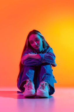 Karşılıksız aşk. Çekici üzgün, üzgün, uzun saçlı, kırmızı arka planda tek başına oturan neon ışıklı bir kız portresi. İlişki kavramı, insani duygular, geçici zorluklar, reklam