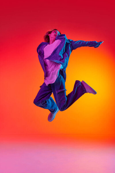 Свободу. Портрет эмоциональной молодой девушки, одетой в повседневную одежду, левитирующую в воздухе на фоне студии красного цвета в неоновом свете. Концепция красоты, молодости, человеческих эмоций, мечтаний, студенческой жизни, рекламы