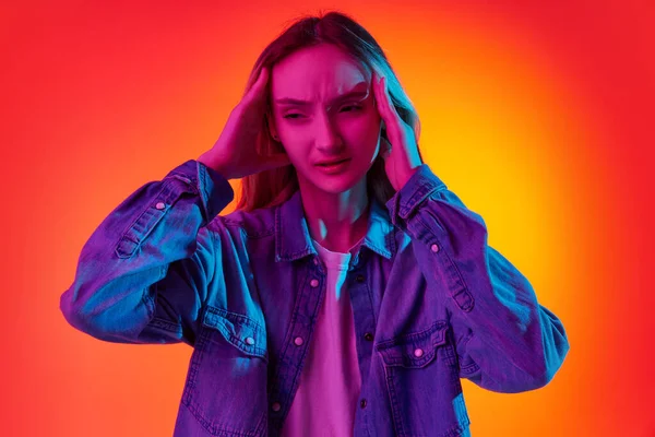 stock image Headache. Portrait with sad, upset teenager, girl with long hair posing over red background in neon light. Concept of treatment, health, youth, human emotions, temporary difficulties, ad