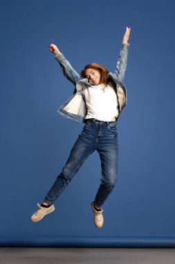 Özgürlük, mutluluk. Güzel, gülümseyen genç bir kızın portresi mavi renkli stüdyonun üzerinden atlayan bir öğrenci. Güzellik, gençlik, yüz ifadesi, insan duyguları, yaşam tarzı kavramı