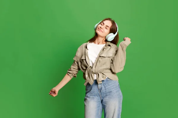 美しい若い女の子 ヘッドフォンのティーンエイジャーの肖像画を閉じ 緑のカラースタジオの背景に喜びを持って音楽を聴く 美しさの概念 人間の感情 — ストック写真