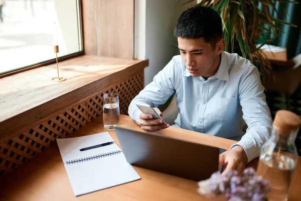 Distance job. Portrait with handsome man, freelancer wearing shirt sitting at cafe and working online on laptop. Freelance work, startup, business people, remote job, career growth, ad concept