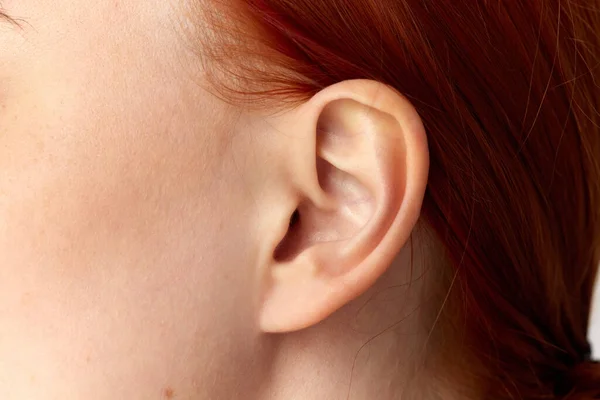 耳垂矫正年轻女孩 白底红头发女孩的耳朵剪成的肖像 关闭图像 整形手术耳朵穿孔 — 图库照片