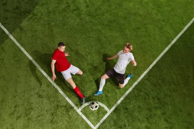 Dinamik çekim. Futbol oyuncuları spor giyer, üniformaları yeşil çim arka planında topa vurur. Eylem kavramı, enerji, spor, takım oyunu, şampiyonluk, rekabet, hareket, reklam