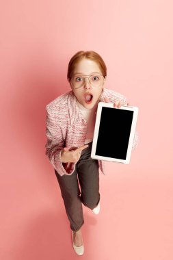 Bir genç kız, elinde tablet olan gözlüklü bir öğrenci ve pembe arka plan üzerinde boş bir cihaz ekranını işaret ediyor. Eğitim kavramı, çevrimiçi, öğrenci hayatı, insan duyguları, sosyal ağlar, reklam