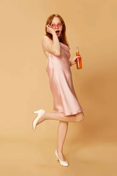 美しい女の子 アルコールでボトルを保持し オレンジの色のスタジオの背景に大学の卒業を祝うドレスの学生 教育の概念 パーティー 人間の感情 — ストック写真