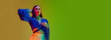 Model kadrosu. Moda mankeni, uzun dalgalı saçlı, yeşil renkli stüdyo ışıkları altında tüylü bluz giyen genç bir kız. Güzellik kavramı, moda haftası, insan duyguları, reklam