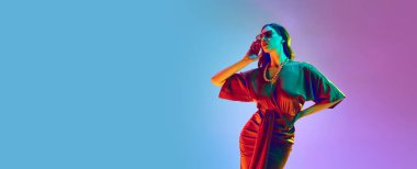 Hayalperest kadın, genç manken menekşe neon arka planda poz veren şık kırmızı elbiseler giyiyor. Reklam afişi. Güzellik kavramı, moda haftası, satışlar, insan duyguları, eğilimler