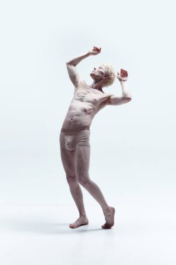 Beyaz arka planda izole edilmiş bir heykel gibi üstsüz poz veren kaslı, yakışıklı, olgun bir adam. Erkek antika heykeli. Erkek vücudu estetiği, erkek güzelliği, ilham, sanat kavramı