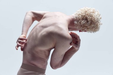 Heykelde poz veren kaslı adam beyaz stüdyo arka planında çıplak poz veriyor. Antik heykel gibi. Arkadan bak. Erkek vücudu estetiği, doğal güzellik, erkek güzelliği, ilham, sanat konsepti.