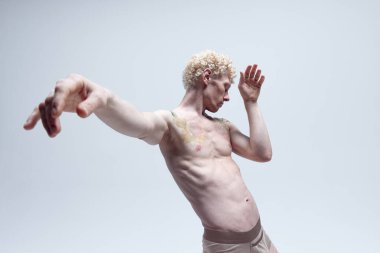 Vücudunda dövmeleri olan kaslı bir adam, beyaz stüdyo arka planında çıplak poz veriyor. Antik heykel gibi. Erkek vücut estetiği, erkek güzelliği, ilham, sanat konsepti.