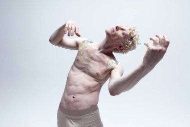 Üzerinde dövmeleri olan sarışın bir adamın beyaz stüdyo arka planında çıplak poz verdiğini hayal ediyorum. Antik heykel gibi. Erkek vücut estetiği, erkek güzelliği, ilham, sanat konsepti.