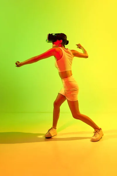 虚拟现实战斗 戴Vr耳机眼镜的女孩在酸绿色和黄色背景下玩游戏 虚拟生活的未来 虚幻世界的概念 数字化 — 图库照片