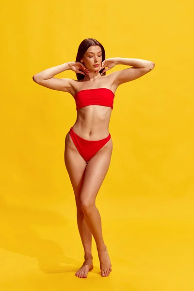 宽慰的身躯 穿着红色泳衣的黑发少女在黄色的工作室背景下摆姿势 夏天的概念 女性的美丽 生活方式 — 图库照片