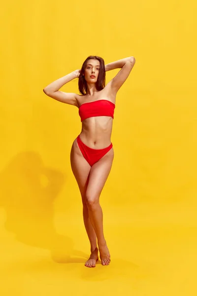 迷人的黑发少女 身强体壮 身强体壮 身强体壮 身穿红色泳衣 背景为黄色 夏天的概念 女性的美丽 生活方式 — 图库照片
