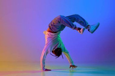 Esnek genç bir adam, break dans yapan düşünceli bir dansçı, neon ışıkta çok renkli bir stüdyoya karşı hip-hop yapıyor. Sokak dansı konsepti, moda, gençlik, hobi, dinamik, reklam