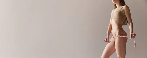 Обрезанный Образ Молодой Женщины Стройным Телом Измеряющим Ягодицы Сером Фоне — стоковое фото