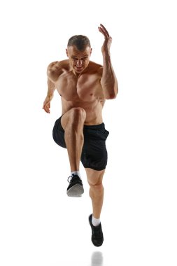 Yakışıklı, kaslı bir adamın ön görüntüsü, hareket halindeki profesyonel bir atlet, beyaz stüdyo arka planında üstsüz koşuyor. Spor, rekabet, sağlık, güç ve hız kavramı, reklam