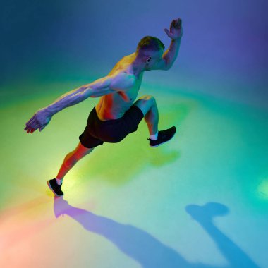 Spor başarıları. İnsanoğlunun en iyi görüntüsü, profesyonel koşucu, hareketli atlet neon ışığı altında gradyan stüdyo arka planına karşı. Spor, rekabet, sağlık, güç ve hız kavramı, reklam