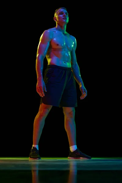 在霓虹灯下 一个身材高大 肌肉丰满 赤身裸体的英俊男子在黑色摄影棚背景下的全长底景形象 广告的概念 — 图库照片