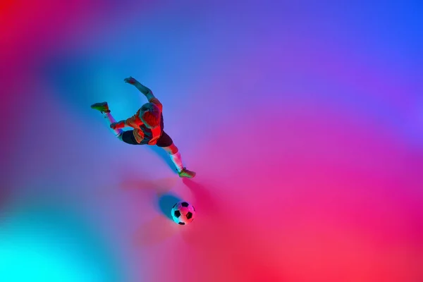 グラデーションのような赤青のネオンでサッカーボールのトレーニング中に小さな男の子を再生する上のビュー アクションの概念 スポーツライフスタイル チームゲーム エネルギー 活力と広告 — ストック写真