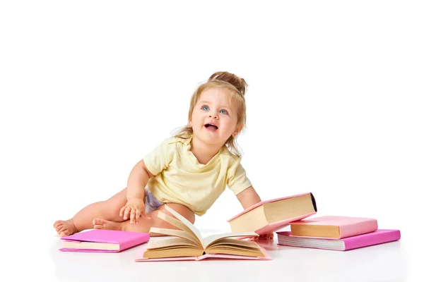賢くて好奇心の強い赤ん坊 小さな女の子 幼児は白いスタジオの背景に対して多くの本で床に座っています 子供時代 誕生の概念 広告のコピースペース — ストック写真
