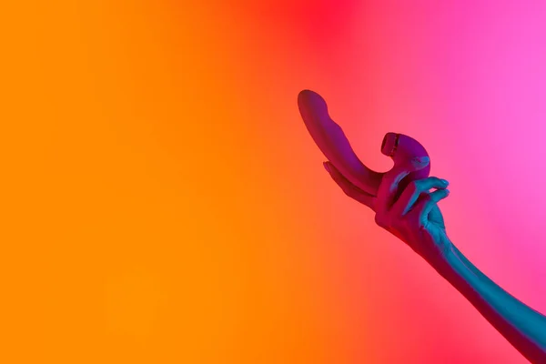女性の手を保持バイブレータ ネオンライトで黄色ピンクの背景にマッサージ 大人のためのおもちゃの概念 健康的なライフスタイル テキストのコピースペース — ストック写真