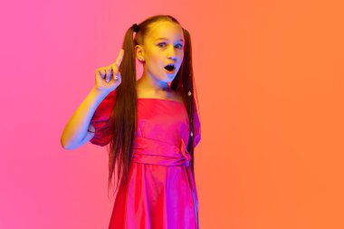 Pembe neon arka planda at kuyruğu pozu veren şenlikli elbiseli küçük bir kız. Çocukluk kavramı, duygular, çocuklar moda, dans, müzik.