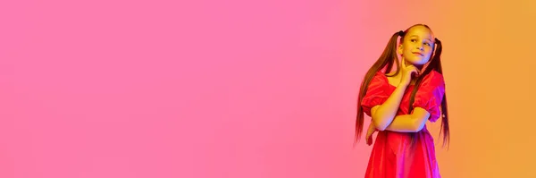 夢を見てる ピンクのネオンの背景の上にポーズポニーテールとお祝いのドレスの魅力的な女の子 子供時代 子供のファッション ダンス 音楽の概念 — ストック写真