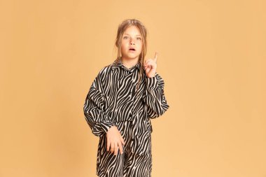 Portrait surprised intellectual girl having good great idea isolated over sandy color background. Concept idea, answer, analyze, question and studying