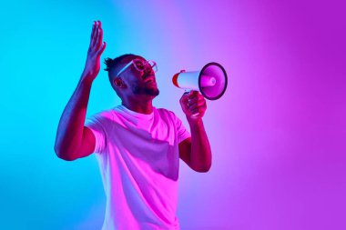 Afro-Amerikalı bir adamın megafonla bağırıp neon renkli stüdyo geçmişiyle el ele tutuşan stüdyo fotoğrafçısı. İnsan duyguları kavramı, soru, haber, evren, satış, reklam