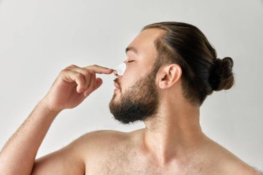 Yatay fotoşopla kafasını çeviren ve deri temizleyici bantlarla burun kısmını izole edilmiş gri arka plan üzerinden burun bölgesine çeviren bir adam. Güzellik kavramı, cilt bakımı, prosedürler, sağlık, reklam.