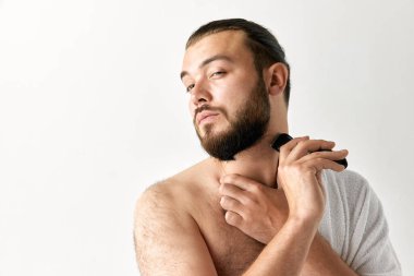 Açık gri arka planda sakal tıraşı olan çekici, bakımlı bir adamın yakın plan portresi. Güzellik, görünüş, yüz bakımı, sağlık, gençlik ve reklam kavramı.