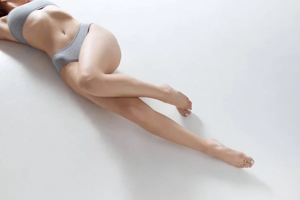 スレンダー 滑らかな足のクロップされたイメージ グレースタジオのバックグラウンドで下着にポーズする女性モデル デポジション エピレーション ボディ スキンケア ウェルネスのコンセプト アドベンチャー — ストック写真