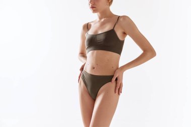Beyaz stüdyo arka planında bej rengi iç çamaşırlı güzel bir kadın vücudu. İnce, desenli vücut şekli. Doğal güzellik kavramı, vücut ve cilt bakımı, sağlık, sağlık, kadınlık. Ad