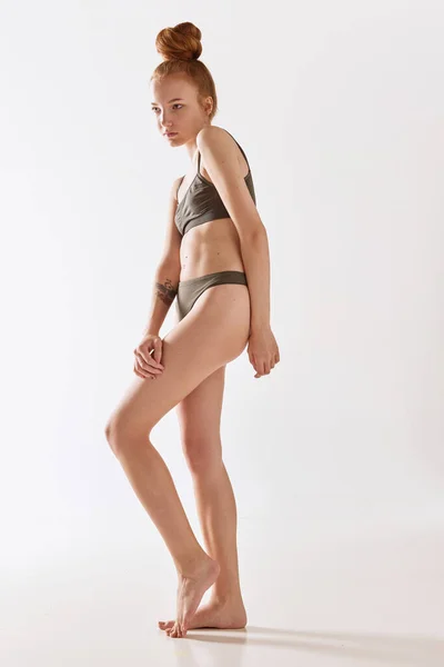 Full lenght photo of young woman with fit body wearing khaki underwear over white background. Concept of natural beauty, body and skin care, health, wellness, femininity. Ad