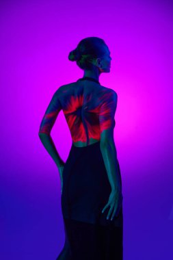 Dijital neon filtre ışıklarındaki yumuşak kadın silueti arkadaki mor renkte kırmızı çiçeği gösteriyor. Arkadan bak. Dijital sanat, moda, gelecekçilik kavramı