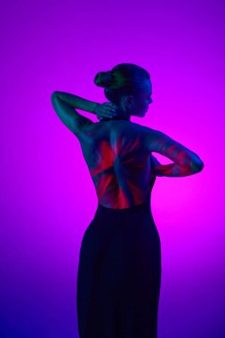 Arkadan bak. Dijital neon filtre ışıklarıyla yumuşatan hassas kadın mor arkaplanda kırmızı çiçek gösteriyor. Dijital sanat, moda, gelecekçilik, güzellik, konsept