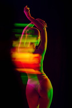 Turuncu ve yeşil ışığın altında üstsüz bir kadın resmi. Arka planda siyah modda uzun pozlama ışıkları var. Duyguların kavramı, güzellik, yüz ifadesi, gençlik, arzu.