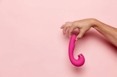 Hanımların elleri vibratörlü, tıbbi masaj aleti pastel pembe arka planda. Seks dükkanı için görüntü. Sağlık kavramı, tıp. Reklam, metin için kopyalama alanı