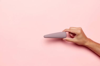 Vibratörlü kadın eli, pastel pembe arka planda tıbbi masaj aleti. Seks dükkanı için görüntü. Sağlık kavramı, tıp. Reklam, metin için kopyalama alanı