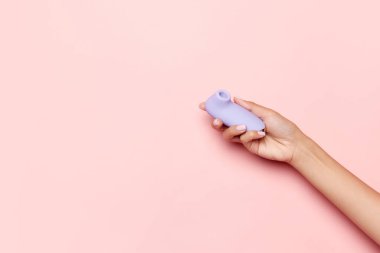 Kadın sağlığı. Vibratörlü kadın eli, pastel pembe arka planda tıbbi masaj aleti. Seks dükkanı için görüntü. Sağlıklı yaşam tarzı ve ilaç kavramı. Reklam, metin için kopyalama alanı