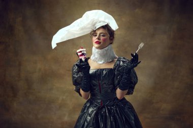 Zarif bir kadın portresi. Polietilen beyaz şapka ve çöp poşetlerinden yapılmış siyah elbise. Elinde tek kullanımlık çatal ve çöl var. Çevre sorunları, geri dönüşüm, tarz, moda kavramı.