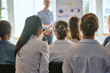 İş koçu. İşletme takımına öğretmenlik yapan dağılmış liderin sunumunu dinlerken bir kadının önünde bir şey göstermesi. Eğitim kavramı, öğrenme