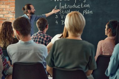 Sunucu, mutlu, başarılı erkek uzman, konuşmacı konferans seminerinde toplantı odasında iş adamlarına öğretmenlik yapıyor. Konferans, eğitim, planlama, öğrenme, koçluk, iş.